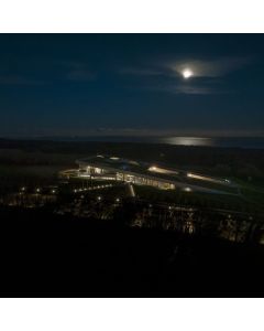 Dronebillede af et oplyst Moesgaard i m&oslash;rket med m&aring;neskin.